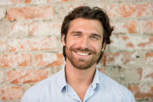 Man smiling against brick wall