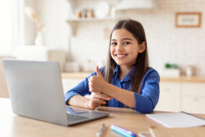 Girl holding thumbs up in front of computer