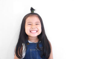Asian children cute or kid girl and kindergarten student happy smile white teeth and laugh with wear dungarees jean for fashion on white background