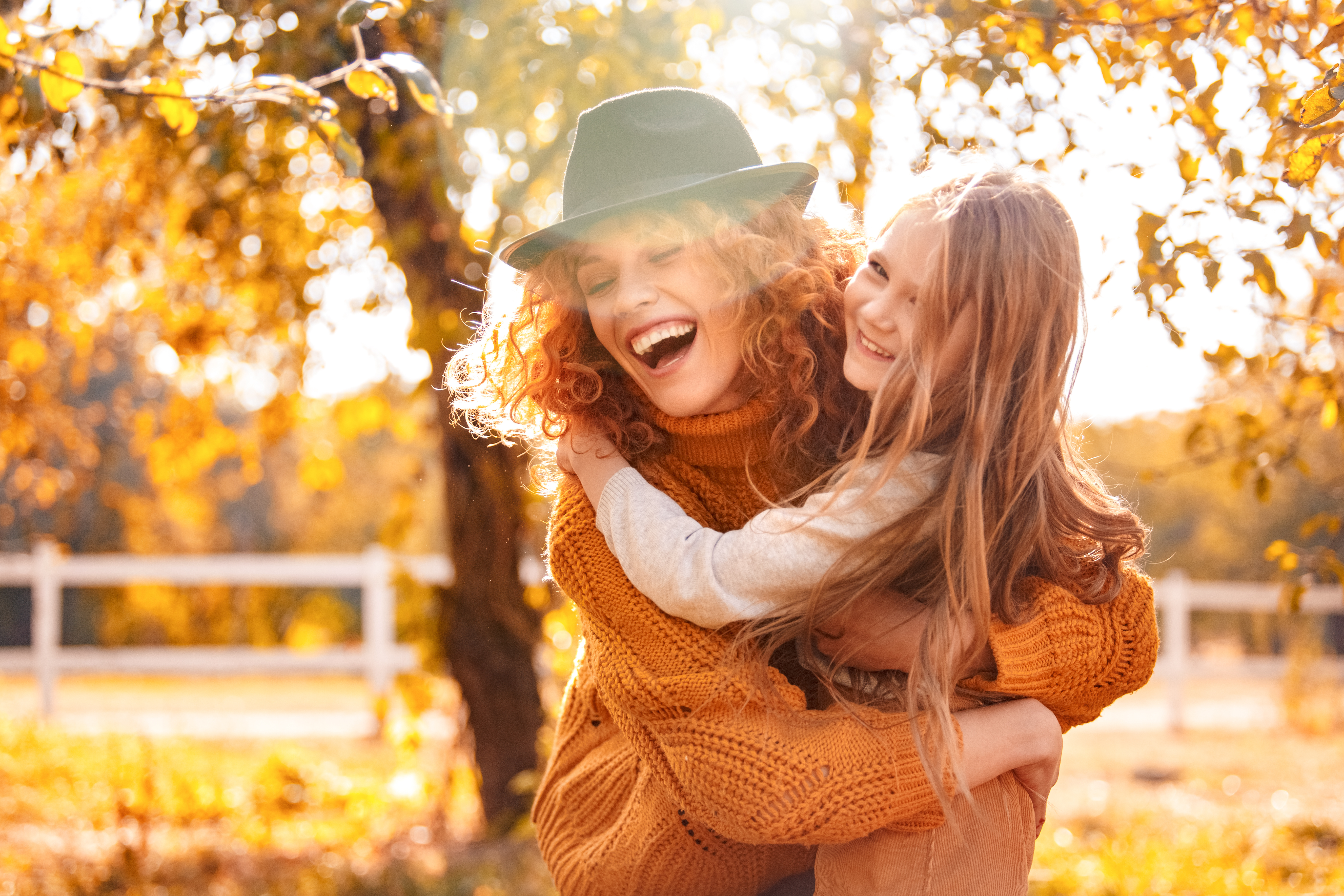 Young adult mother hugging her lovely child girl and laughing. Little daughter cuddling to mom and smiling wide, while they spending autumn day together dental habits